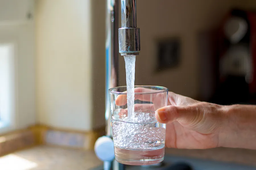closeup of kitchen faucet filling drinking glass