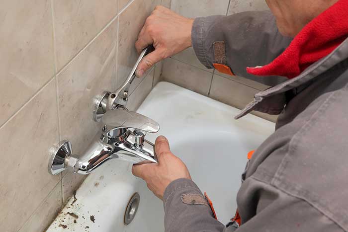 Plumber installing or repairing a bathtub faucet