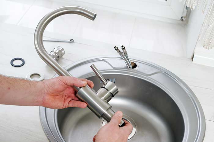 Plumber installing a new kitchen faucet