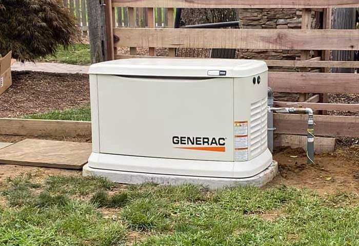 Generac standby generator installed outside near a fence.