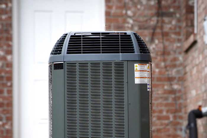 Outdoor air conditioning unit installed near a brick wall