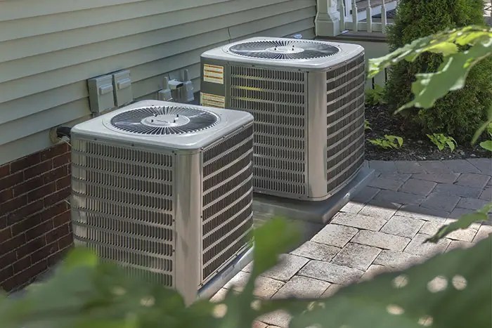 Two outdoor air conditioning units installed on a paved area