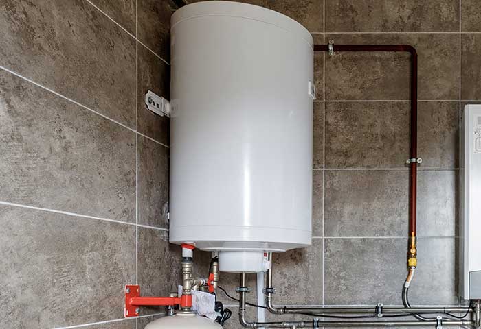 Wall-mounted hot water storage tank with connected pipes