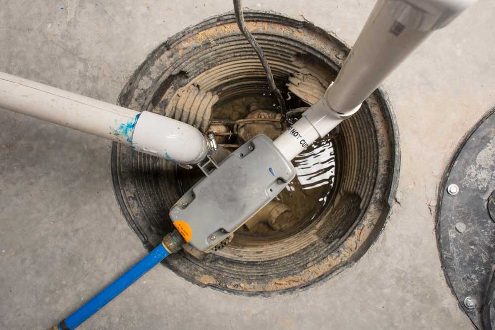Open sump pump with connected pipes and water inside