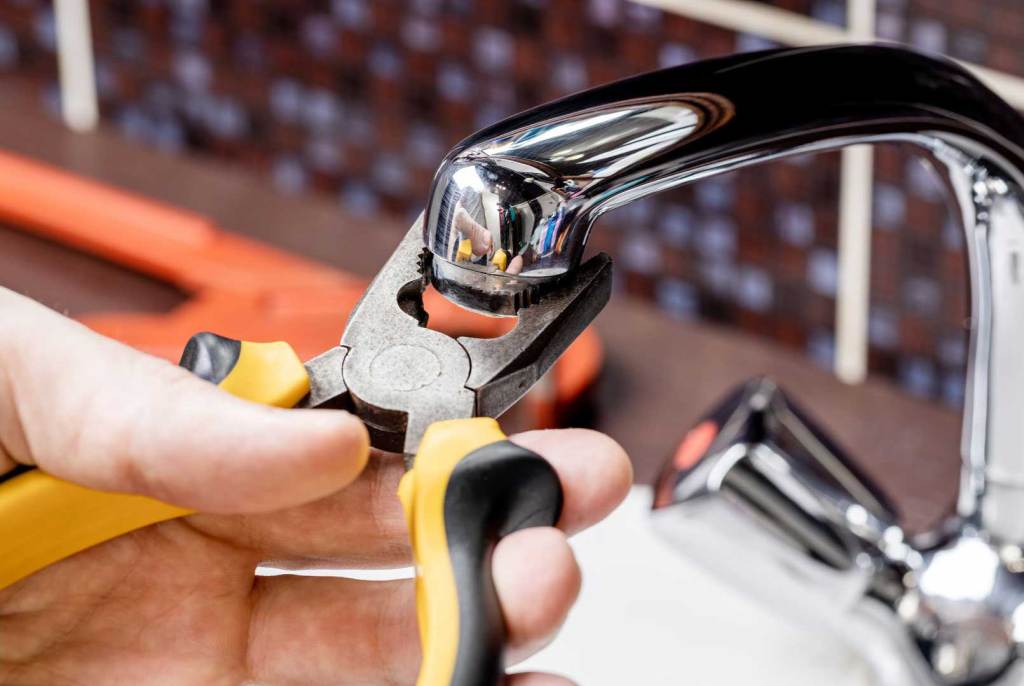 Plumber using pliers to repair a faucet