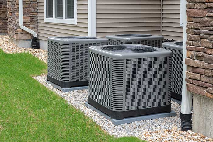 Four outdoor air conditioning units installed on gravel beds